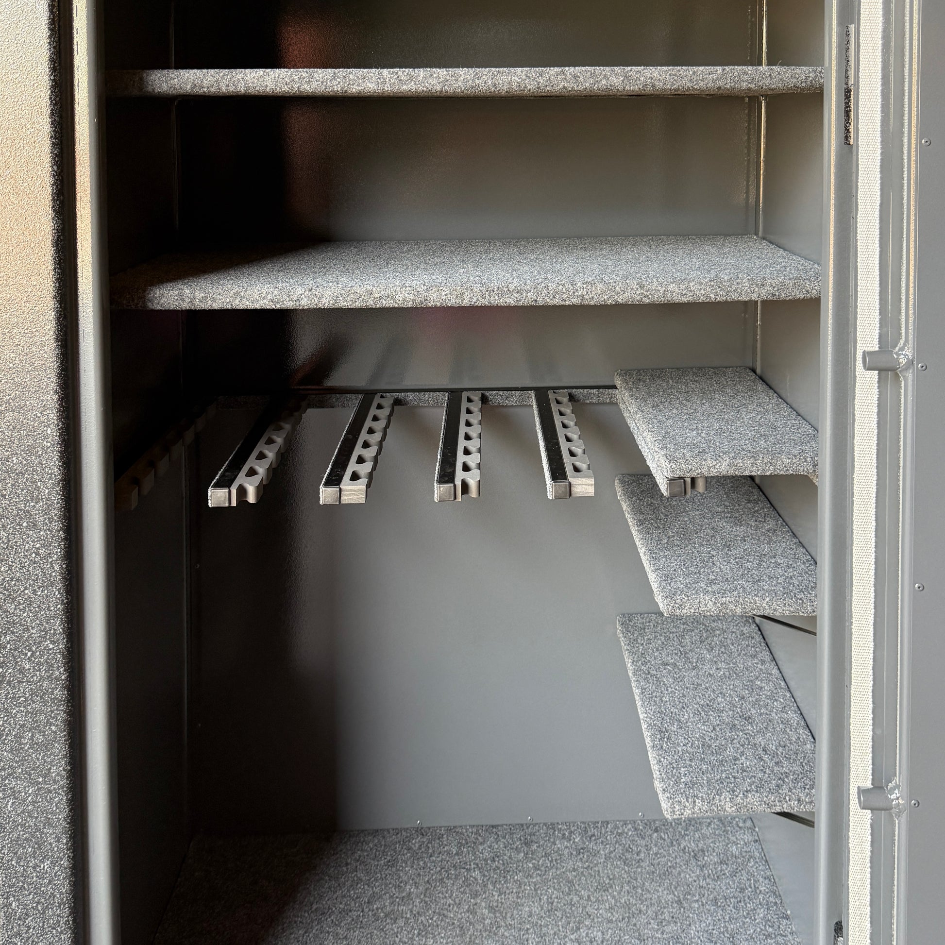 gun safe interior shelving unit with gray shelves and metal gun rack.