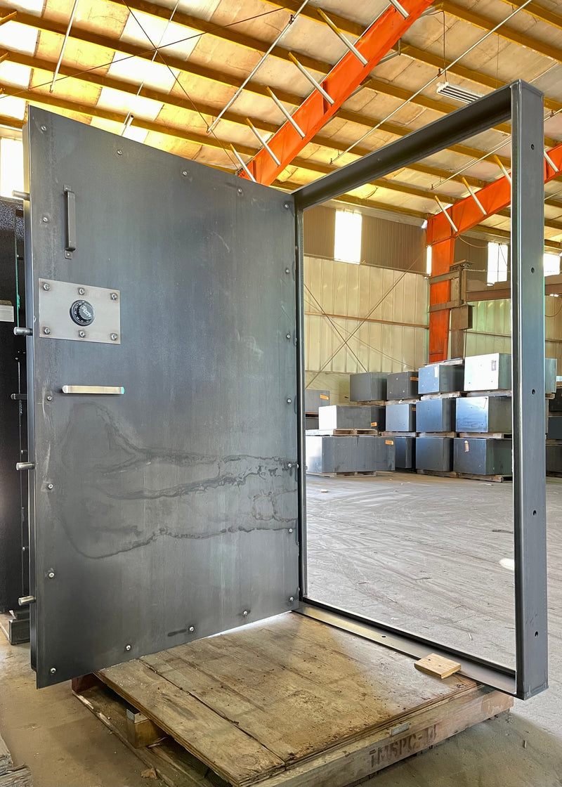 extra wide vault door in a warehouse setting with stacks of boxes in the background.