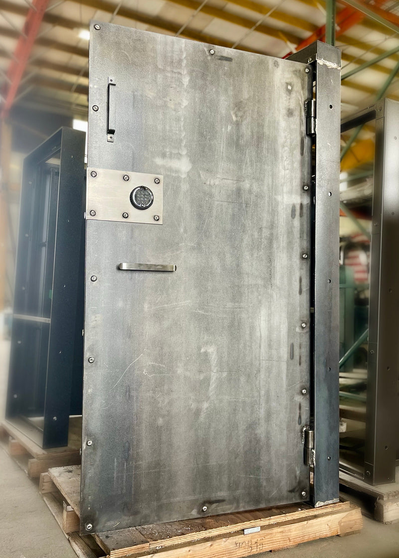 Large metal vault door on a wooden pallet in an industrial setting