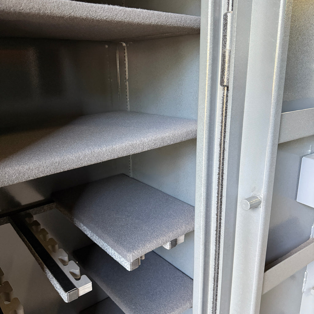 Gray shelves inside a gun safe with a partially open door.
