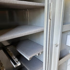 Gray shelves inside a gun safe with a partially open door.